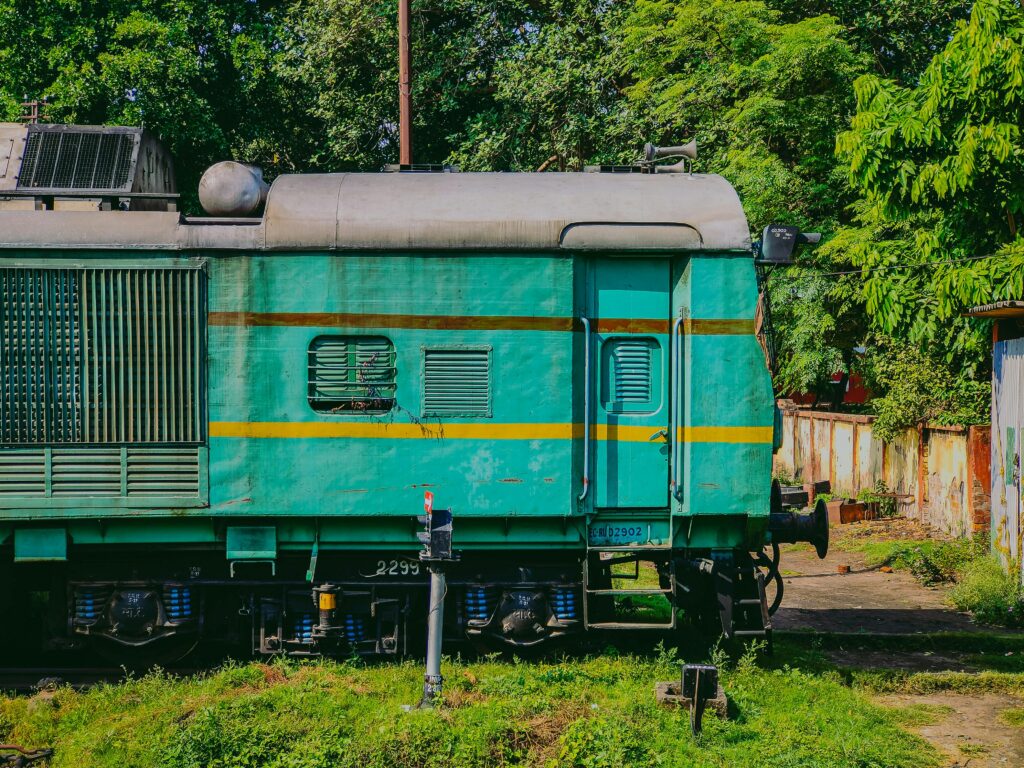 Vivid green train engine resting on railway tracks surrounded by lush greenery.